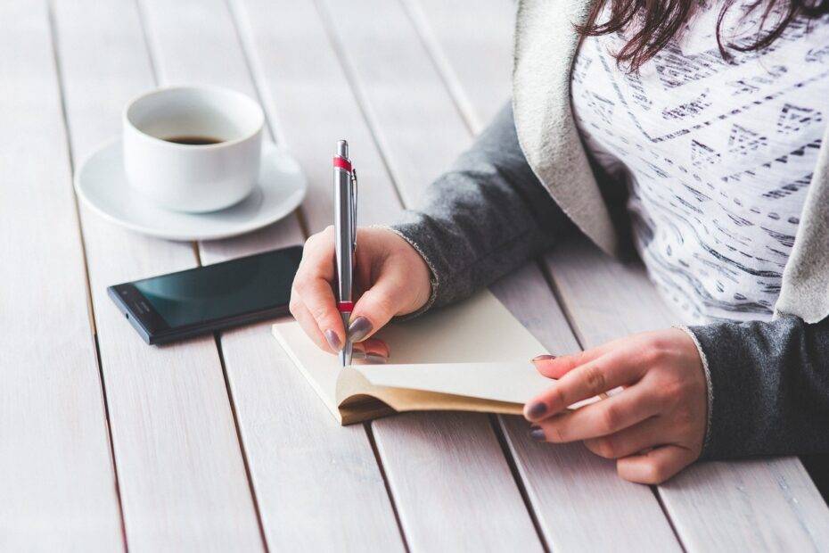 Photo of a woman writing with a cup of coffee